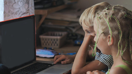 Children are browsing photos on a laptop.