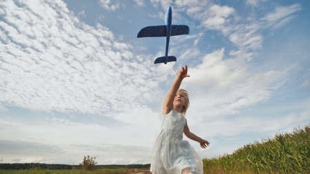 A little girl runs and launches a paralon toy airplane.の写真素材