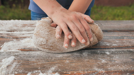 Girl hands in flour closeup kneading dough on table