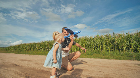 Father and little daughter launch a foam rubber toy airplane.