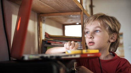 A boy of seven years old is watching something on a laptop.