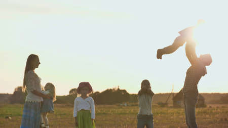 Happy parents of 4 children toss up their children.の写真素材