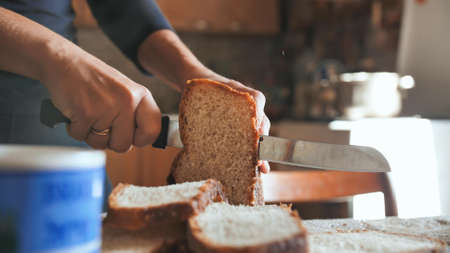 Cooking breakfast. A young woman cuts bread.の写真素材
