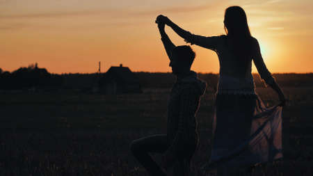 Silhouettes of a dancing couple in love at sunset.の写真素材