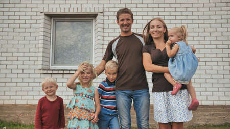 A large family with four children in front of their own home.の写真素材