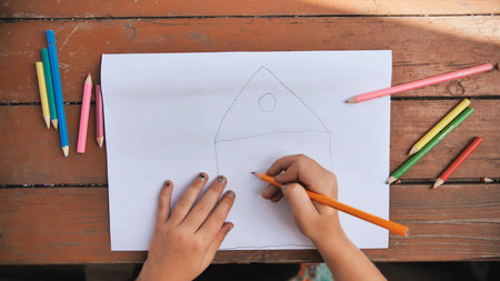 Child draws a pencil drawing of the house and his family. New home.の写真素材