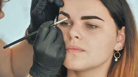 Permanent makeup. Permanent tattooing of eyebrows. Cosmetologist applying permanent make up on...