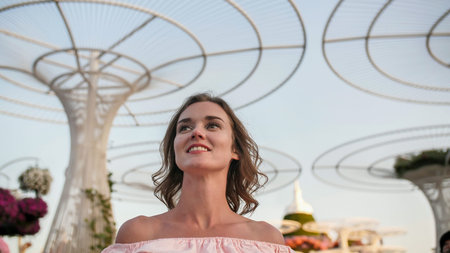 Girl on the background futuristic metal flowers in Dubai Miracle Garden Park.