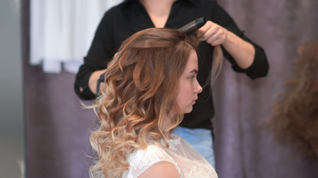 Girl hairdresser doing hairstyle in the form of spinning hair.
