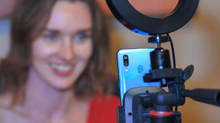 A beautiful girl broadcasts live at home using a phone.の写真素材