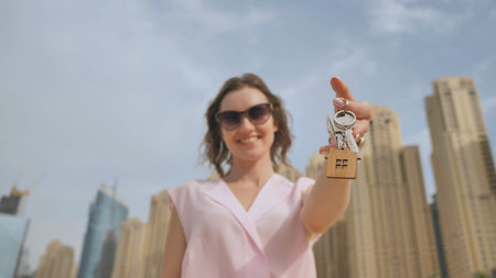 The concept of buying an apartment. Girl holds the keys to a new house against the backdrop of...