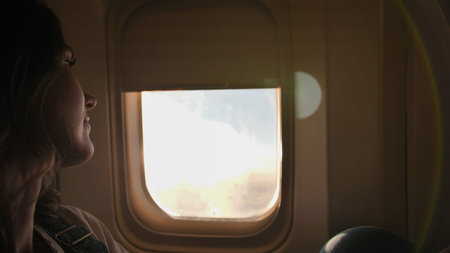 A young woman sits by the window in the cabin at duskの写真素材