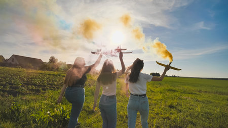 Happy friendly friends are running with toy planes that emit colored smoke.