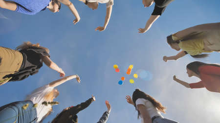 A group of friends release colorful balloons into the sky.の写真素材