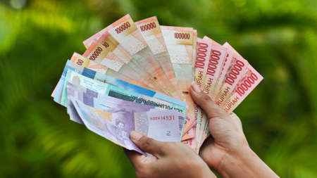 The girl is holding Indonesian money. Indonesian rupeeの写真素材