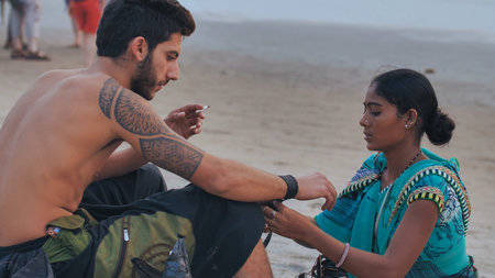 A female saleswoman offers decoration to a tourist on Arambol beach.