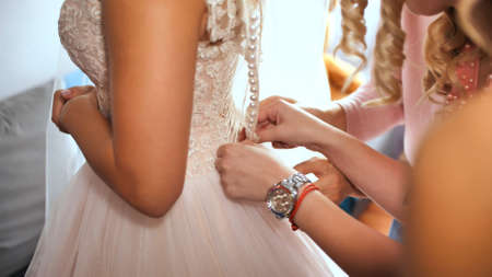 bride's girlfriend helps bride dress up her wedding dressの写真素材