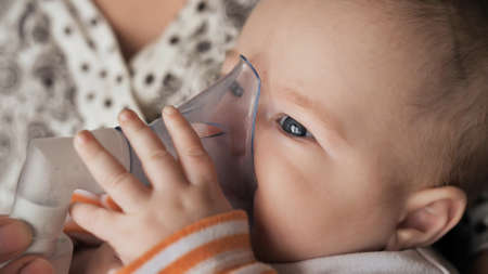 Funny one year old baby breathes with an inhalerの写真素材