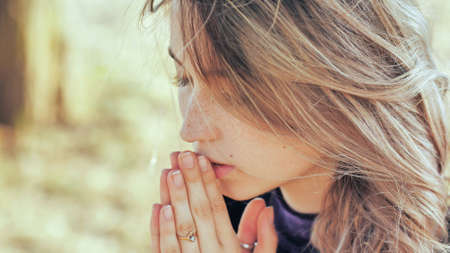 A young blonde 18 year old girl prays with folded hands.の写真素材