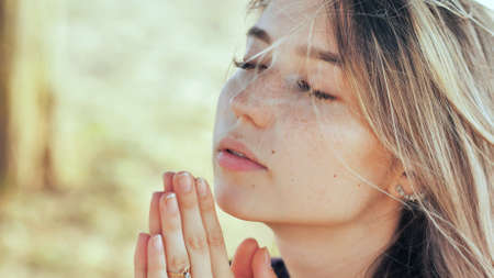 A young blonde 18 year old girl prays with folded hands.の写真素材