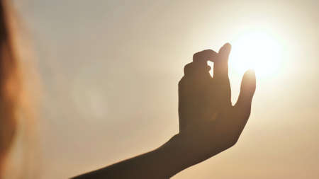 The girl touches the sunset sun the fingers. Romantic conceptの写真素材