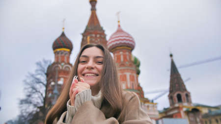 Happy smiling young woman portrait in Red Square, Moscow. A woman in the city warms her hands.の写真素材
