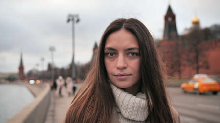 Sad girl in a coat in the city posing for the camera. Woman walks near the walls of buildings on the streets of Moscow.の写真素材