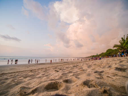 Kuta, Bali, Indonesia - January 15, 2019: Tourists at sunset sit on a popular tourist beach in Bali.のeditorial素材