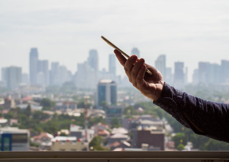 A man uses a phone against the backdrop of a panorama of a metropolis.の写真素材