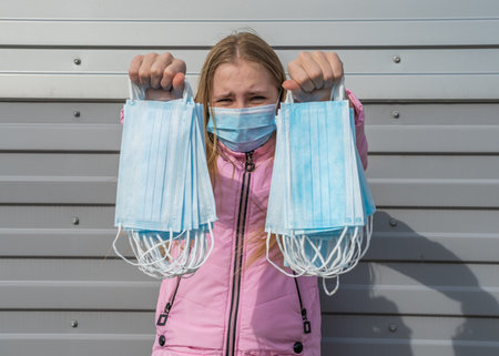 Concept of coronavirus quarantine. Teenager girl in a mask with many masks in her hands.
