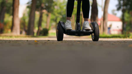 Teenager girl in a park riding a gyro scooter. Legs close upの写真素材