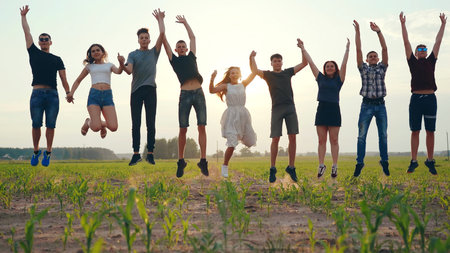 Happy friends jumping holding hands at sunset.