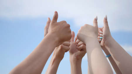 A group of friends raise their hands with their fingers up.の写真素材