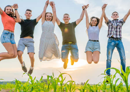 Happy friends are jumping at sunset on a summer evening.の写真素材