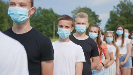 Pandemic concept. A group of students stand in a row in masks.の写真素材