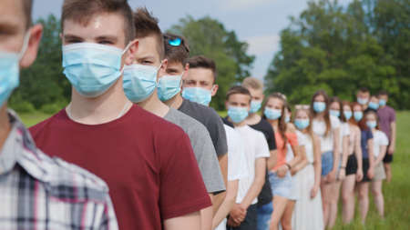 Pandemic concept. A group of students stand in a row in masks.の写真素材