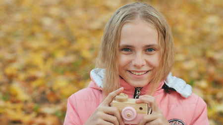 Teenage girl with toy cameras takes pictures in the autumn park.