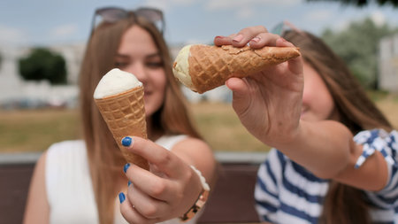 Two girls are presenting ice cream to the viewer.