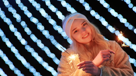 Girl with sparklers on the background of the Christmas lights of the evening city.