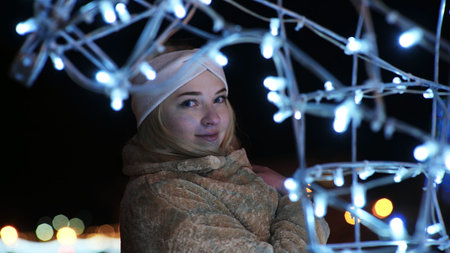 Girl posing against the backdrop of urban Christmas illumination.の写真素材