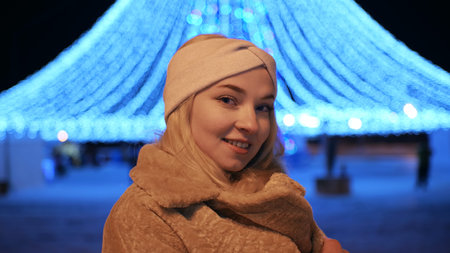 Girl posing against the backdrop of urban Christmas illumination.