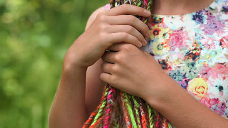 A teenage girl strokes her colorful dreadlocks with her hand.の写真素材