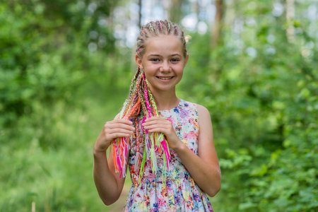 Teenage girl with multi-colored dreadlocks in the forest.