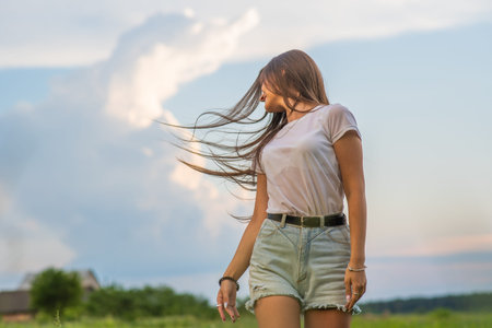 Long-haired girl posing in a field on a summer evening.