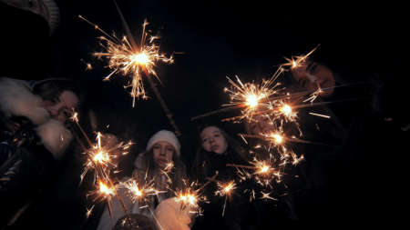 Happy friends join hands with sparklers in the center.の写真素材