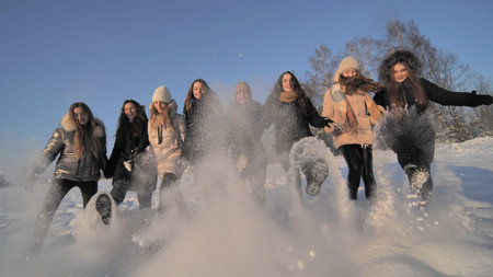 Cheerful girls friends kick the snow with their feet.の写真素材