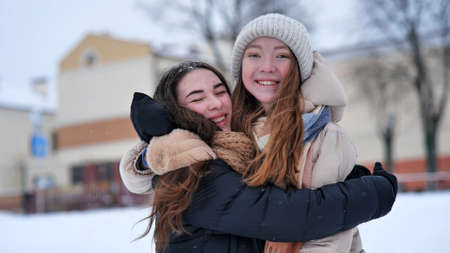 Portrait of two young smiling and hugging girls in the winter in the city.の写真素材