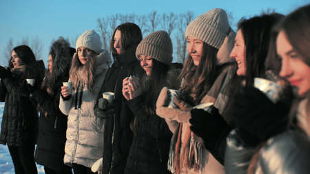 A group of girls are drinking hot tea in winter.の写真素材