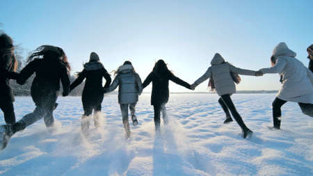 Cheerful girls run across the snow-covered field.の写真素材