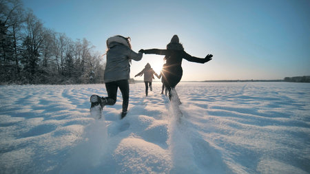 Cheerful girls run across the snow-covered field.の写真素材